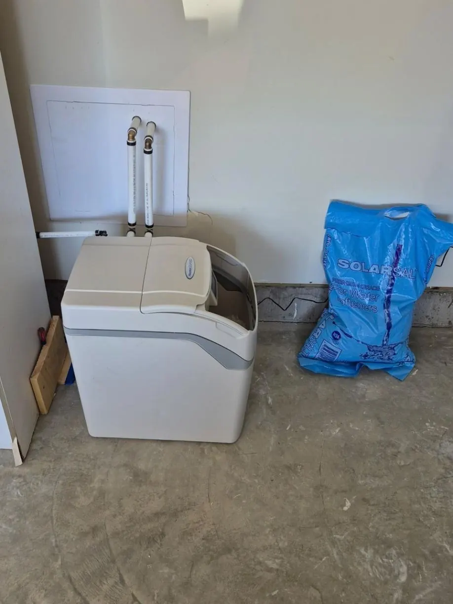 Hague HomeGuard cabinet softener in a garage, next to a bag of softener salt