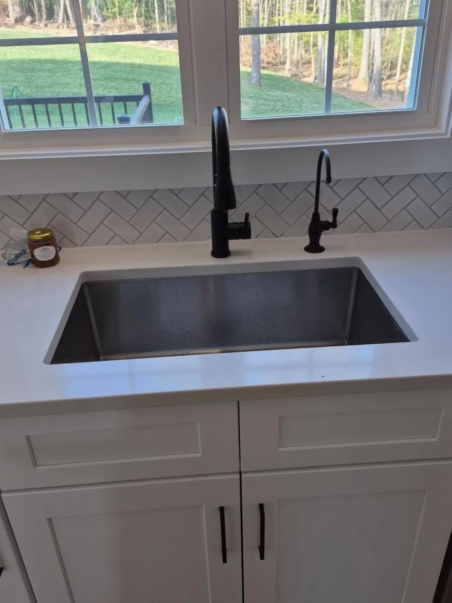 Black reverse osmosis faucet at a kitchen sink under a window
